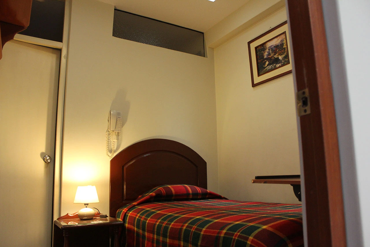 Habitación individual con colcha a cuadros y lámpara de noche